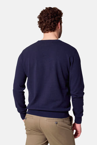 Donkerblauwe trui met ronde hals van Bruce & Butler, gezien vanaf de achterkant, gecombineerd met een kaki broek.
