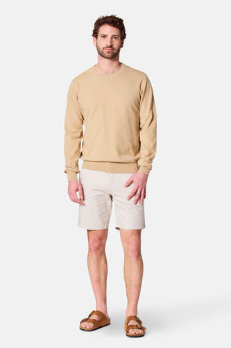 Pull beige avec col rond de Bruce & Butler, porté avec des shorts crème et des sandales brunes.