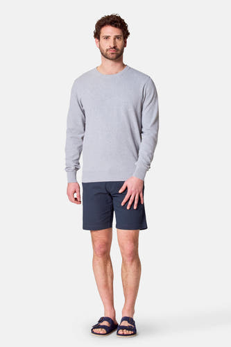 Sweat-shirt gris avec col rond de Bruce & Butler, porté avec des short bleus et des sandales.