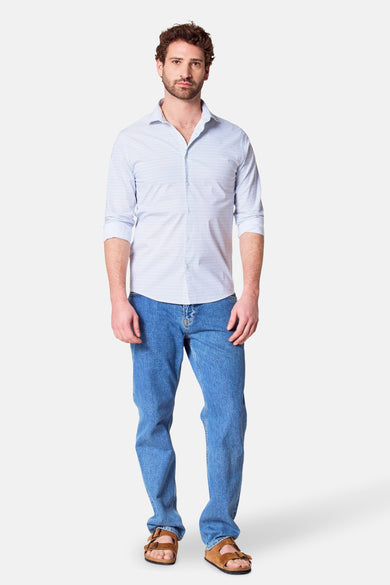 Een man draagt een blauw geruit overhemd, jeans en bruine sandalen.