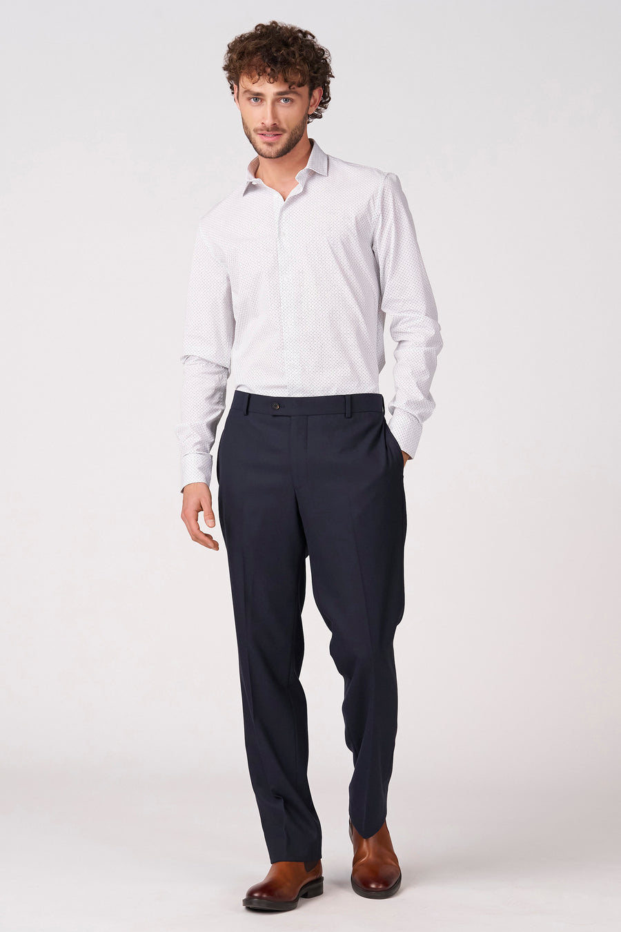 Wit overhemd met lange mouwen van Bruce & Butler, voorzien van een subtiel stippenpatroon en gedragen met een donkerblauwe pantalon en bruine schoenen.
