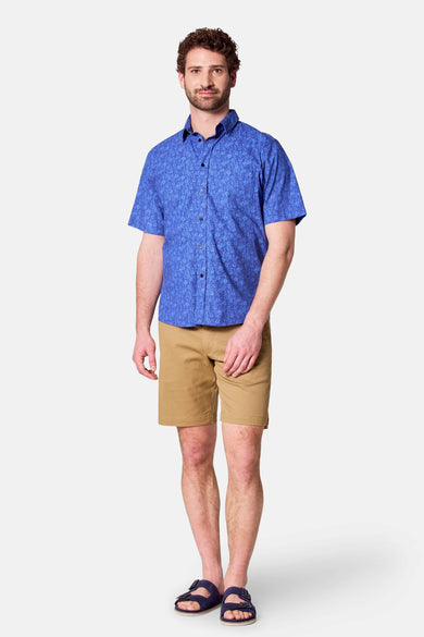 Chemise bleue à manches courtes de Bruce & Butler, avec un motif floral et portée avec des shorts kaki.