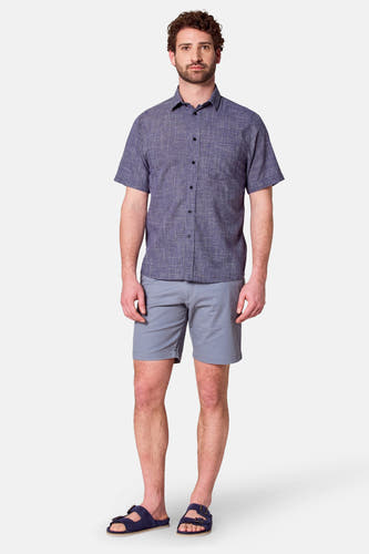 Blauw overhemd met korte mouwen van Bruce & Butler, met een subtiel ruitpatroon, gecombineerd met grijze shorts en sandalen.
