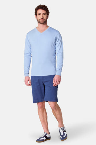 Shorts bleus de Bruce & Butler, portés avec une chemise bleue claire et des baskets bleues et blanches.