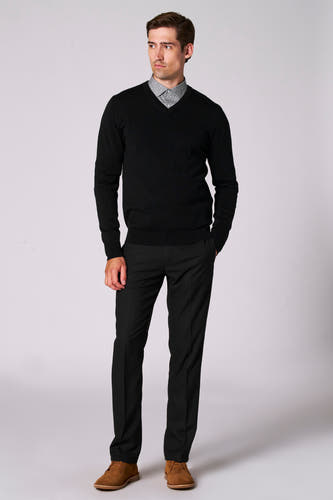 Pull noir à col V de Bruce & Butler, porté sur une chemise imprimée, associé à un pantalon noir et des chaussures en cuir marron.