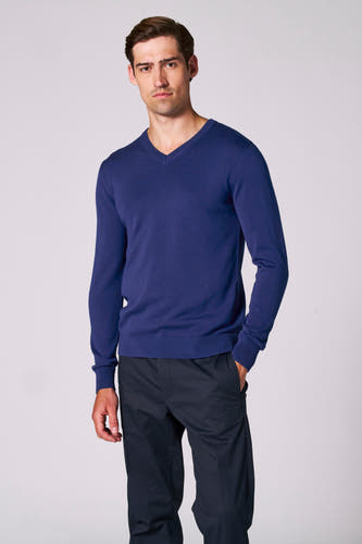 Blauwe V-hals trui van Bruce & Butler, met lange mouwen en gecombineerd met een donkere pantalon.