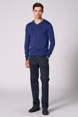 Blauwe V-hals trui van Bruce & Butler, gecombineerd met donkere pantalon en veterschoenen.