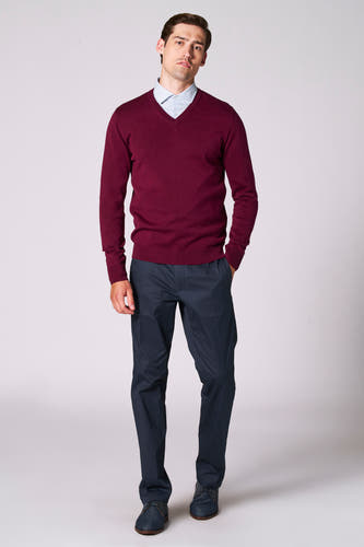 Gilet de Bordeaux avec col V de Bruce & Butler, porté sur une chemise bleue claire à motif et un pantalon bleu foncé.