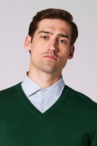 T-shirt à col V vert de Bruce & Butler, porté sur une chemise à motif bleu.