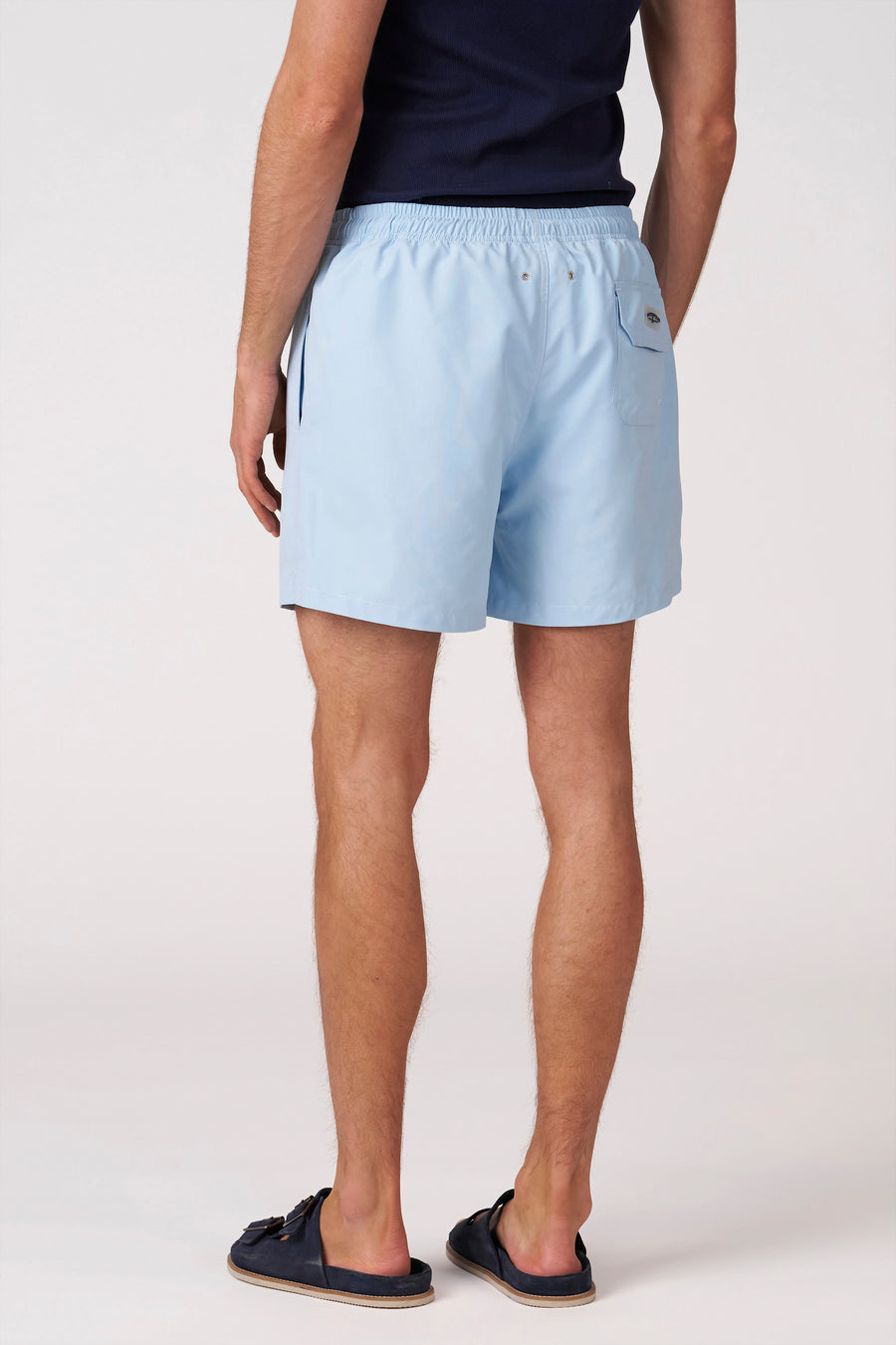 Short de bain bleu de Bruce & Butler, vu de dos, avec taille élastique, poche arrière et œillets métalliques.