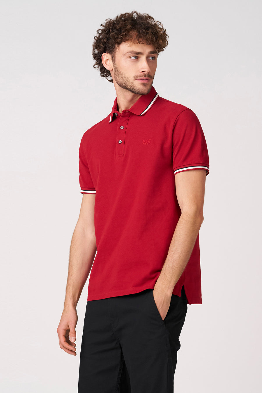 Polo rouge à manches courtes de Bruce & Butler, avec un passepoil blanc au col et aux manches.