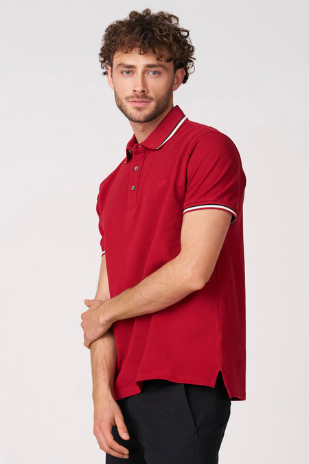 Polo rouge à manches courtes de Bruce & Butler, avec passepoil blanc et noir au col et aux manches.