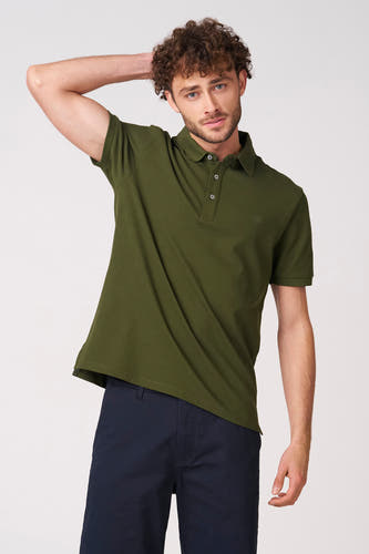 Polo verte à manches courtes verte de Bruce & Butler, vue de dos avec les bras croisés et un pantalon foncé.