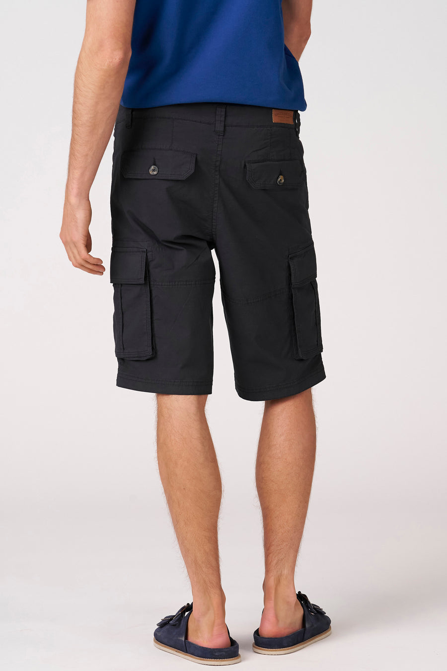 Zwarte Bermuda's van Bruce & Butler, achterkant met zakken, model in blauw shirt en slippers