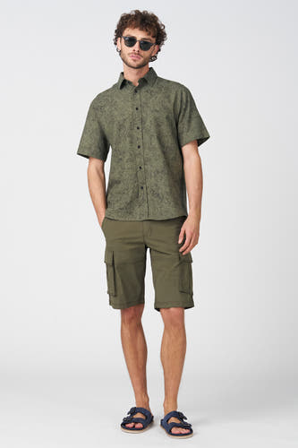 Kaki Bermuda's van Bruce & Butler met zakken, gedragen met een groene overhemd en blauwe slippers, front view.
