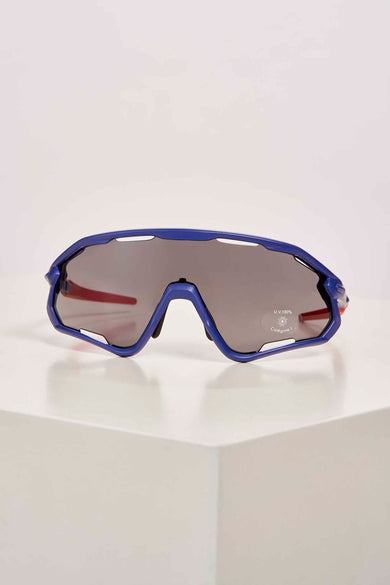 Blauwe sportzonnebril van Cyclo Club Marcel met donkere glazen en rode details, zijwaarts op witte ondergrond