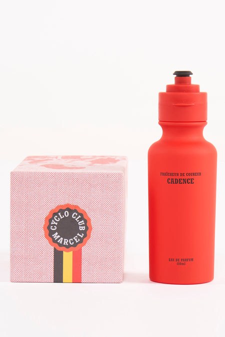 Rode parfum drinkfles van Cyclo Club Marcel, staand naast een kartonnen doos met een rood stippenpatroon en logo.
