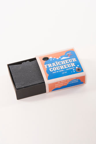 Savonnette noire de Cyclo Club Marcel dans un emballage en papier avec des détails bleus et oranges.