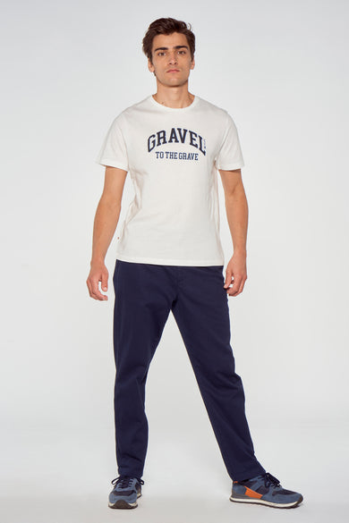 T-shirt blanc à manches courtes avec texte bleu foncé "GRAVEL TO THE GRAVE" de Cyclo Club Marcel, porté par un mannequin en pose lifestyle