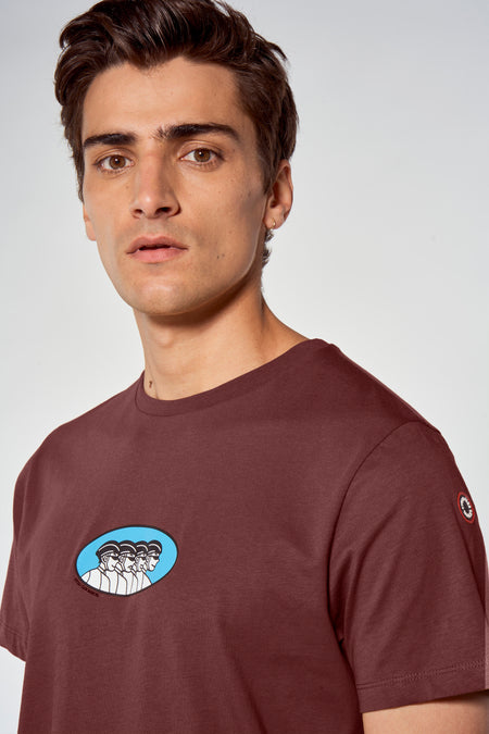 Bruine korte mouw t-shirt van Cyclo Club Marcel met blauwe ovale print en logo op mouw, gedragen door model in close-up.