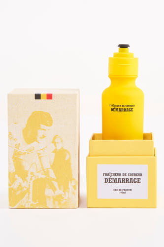 Gele parfum van Cyclo Club Marcel in een doos met illustraties van fietsers.

