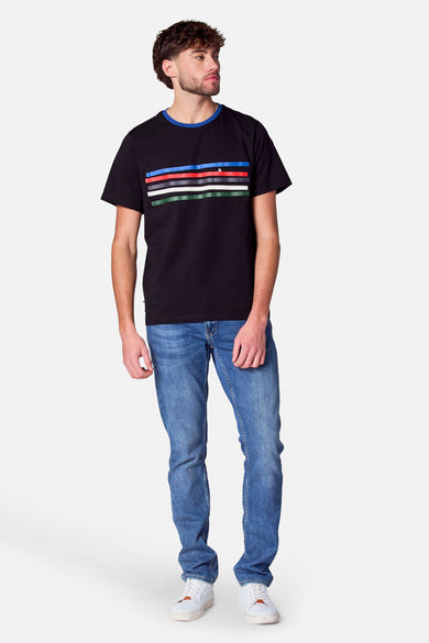 Zwart T-shirt met korte mouwen van Cyclo Club Marcel, met gekleurde horizontale strepen en gedragen met blauwe jeans en witte sneakers.
