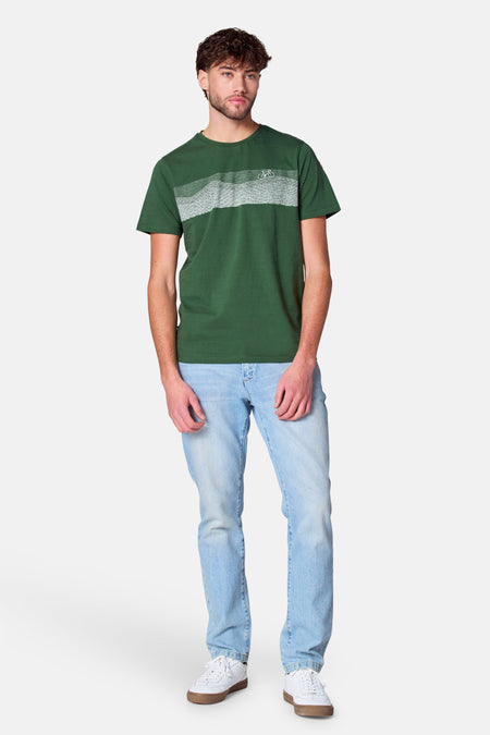 T-shirt vert avec manches courtes de Cyclo Club Marcel, à rayures horizontales et un petit logo de vélo, associé à une légère jean et des baskets blanches.