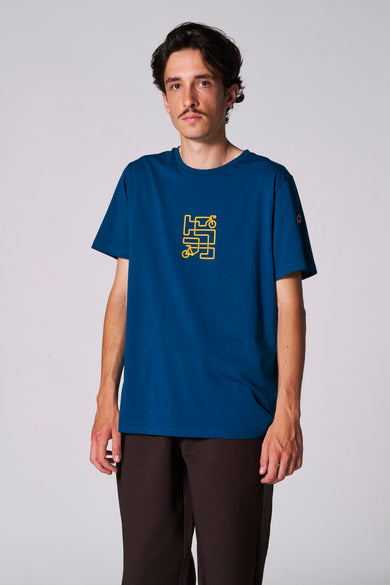 Blauw T-shirt met korte mouwen van Cyclo Club Marcel, met gele fiets-graphic op de borst, gecombineerd met een bruine broek.
