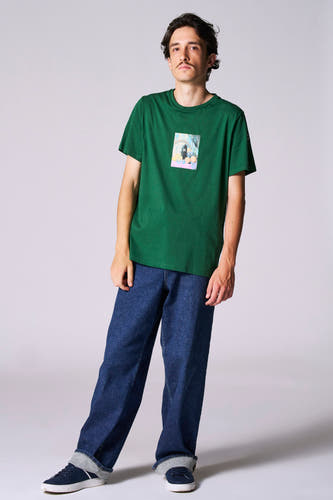 Groen T-shirt met korte mouwen van Cyclo Club Marcel, met een kleine afbeelding op de borst, gecombineerd met donkerblauwe jeans en sneakers.
