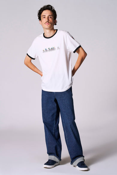Wit T-shirt met korte mouwen van Cyclo Club Marcel, met opdruk van fietsers en gedragen met jeans en sneakers.
