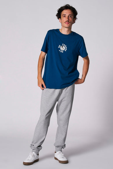 Blauw T-shirt met korte mouwen van Cyclo Club Marcel, met witte print, gecombineerd met grijze joggingbroek en witte sneakers.
