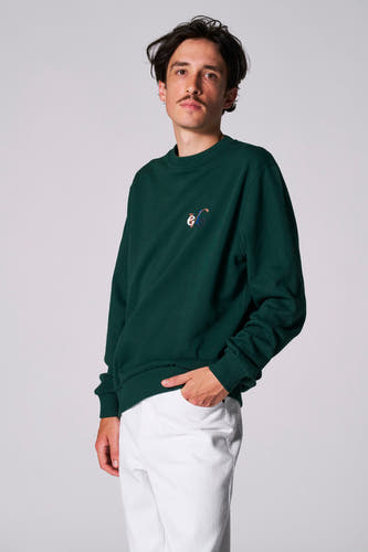 Groene trui van Cyclo Club Marcel met geborduurd logo, gedragen met een witte broek.