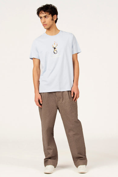 T-shirt bleu à manches courtes de Cyclo Club Marcel, avec imprimé et porté avec un pantalon marron et des chaussures blanches.