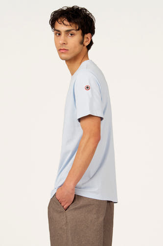 T-shirt bleu à manches courtes de Cyclo Club Marcel, avec un petit logo sur la manche, porté avec un pantalon marron.