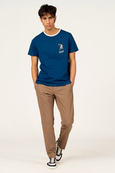 Blauw T-shirt met korte mouwen van Cyclo Club Marcel, met een print op de borst en gecombineerd met bruine broeken en sneakers.

