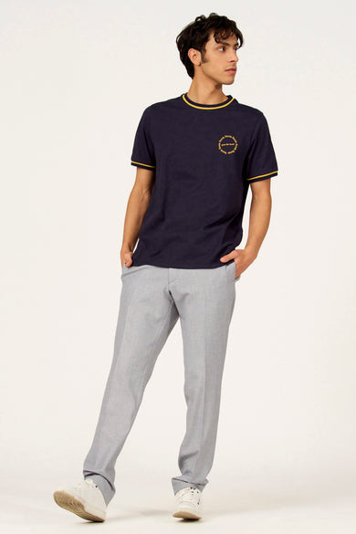 T-shirt bleu à manches courtes de Cyclo Club Marcel, fini avec des accents jaunes et un logo, combiné avec un pantalon gris et des baskets blanches.