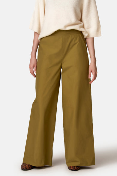 Groene wijde broek van COPINES D'ANVERS, gedragen met een crèmekleurige trui en schoenen met slangenprint.