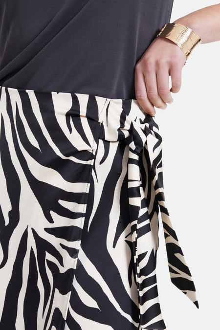 Lange multicolor rok van NAF NAF, met zebraprint en een knoopdetail aan de zijkant, close-up.
