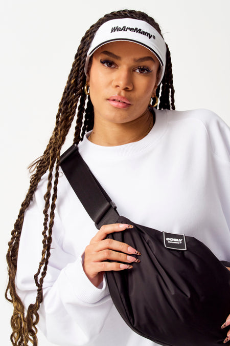 Chapeau blanc de COELY porté par une personne avec des cheveux tressés et un sac noir sur l'épaule.