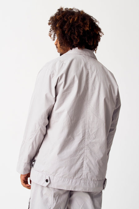 Grijze korte jas van COELY, gezien van achteren met donker krullend haar en grijze broek.