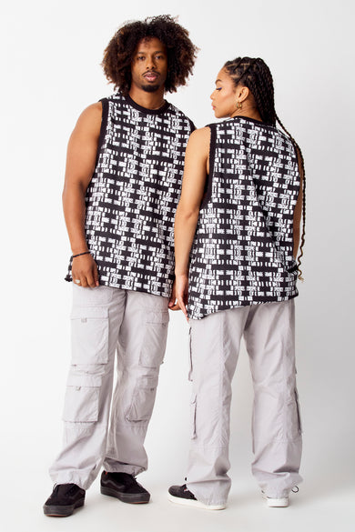 Grijze cargobroek van COELY, met meerdere zakken en gedragen met een zwart-wit bedrukte tanktop.
