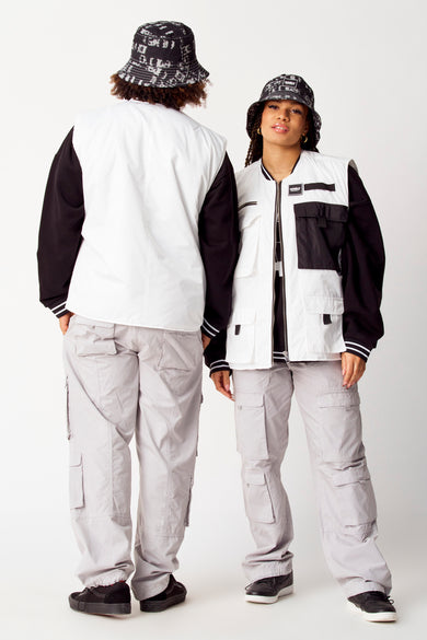 Manteau blanc de COELY, porté avec un haut noir et un pantalon cargo gris, ainsi qu'un chapeau panier coordonné.