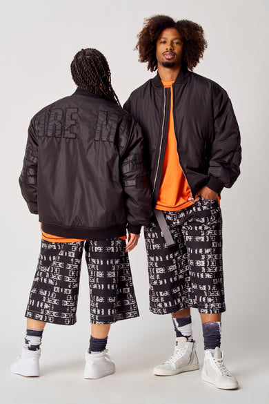 Manteau court noir de COELY, avec le texte "DREAM" sur le dos et des détails rayés sur les manches.