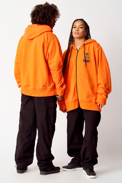 Zwarte cargobroek van COELY, gedragen met een oranje hoodie en zwarte sneakers.
