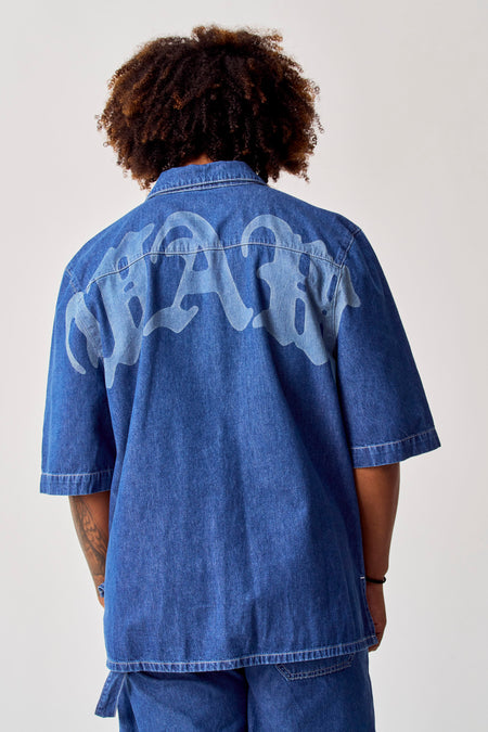 Blauw jeanshemd van COELY, met een groot letterpatroon op de rug.