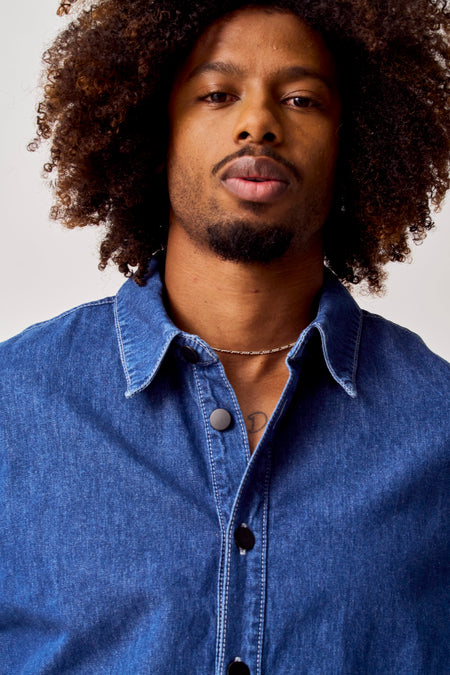 Blauw jeanshemd van COELY, met zwarte knopen en zilveren ketting.