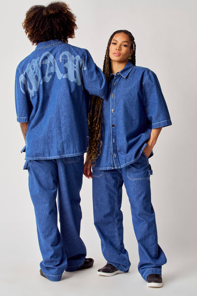 Blauw jeanshemd van COELY, met korte mouwen en knoopsluiting, gecombineerd met bijpassende jeansbroek.
