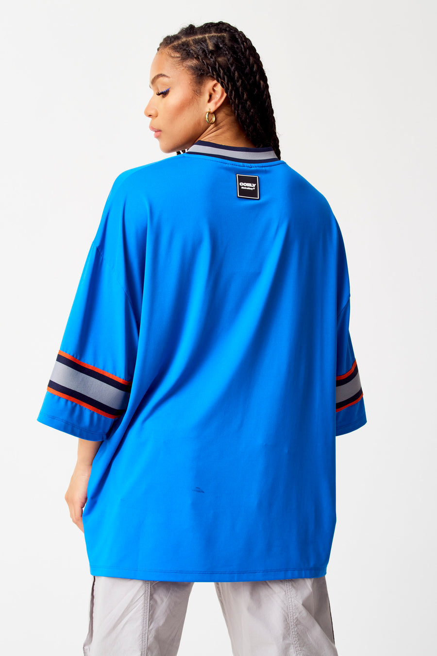Blauwe top van COELY, met gestreepte details op de mouwen en een label in de nek.