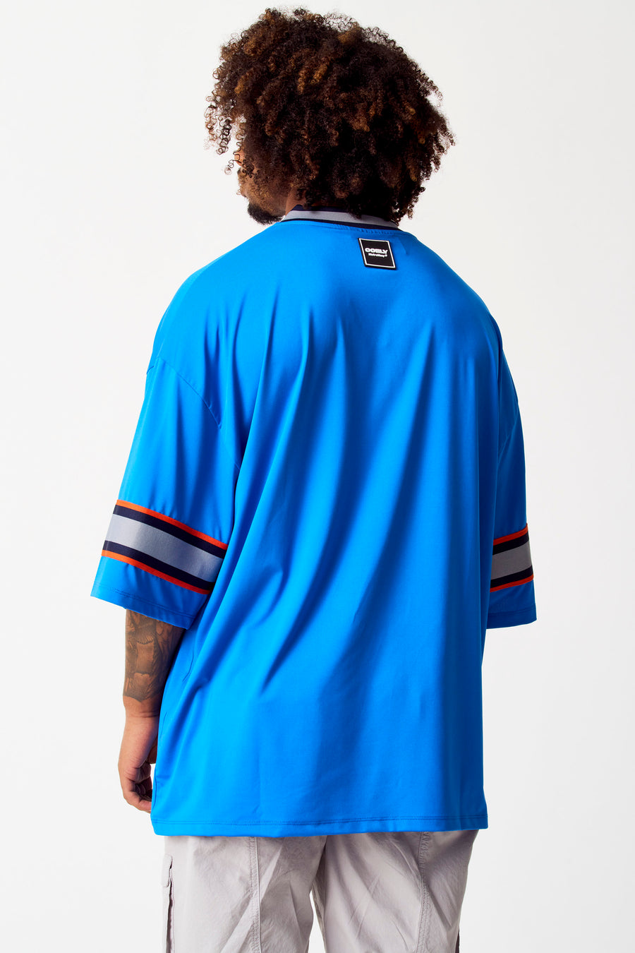Blauwe top van COELY, met gestreepte mouwen en een label in de nek.