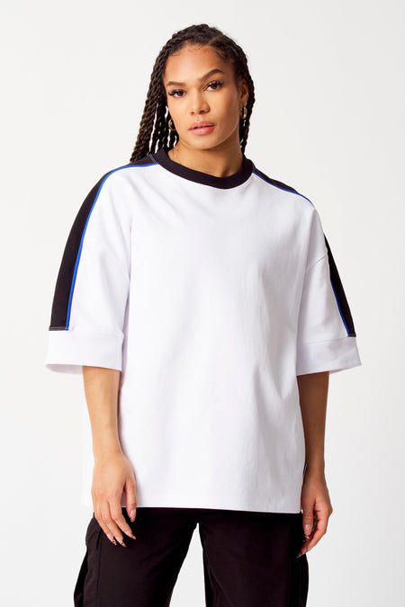 Pull-over blanc avec col rond de Coely, avec des détails noirs et bleus sur les manches.
